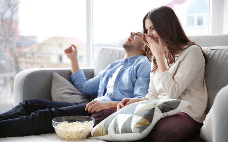 Happy couple laughing as they watch their wedding video