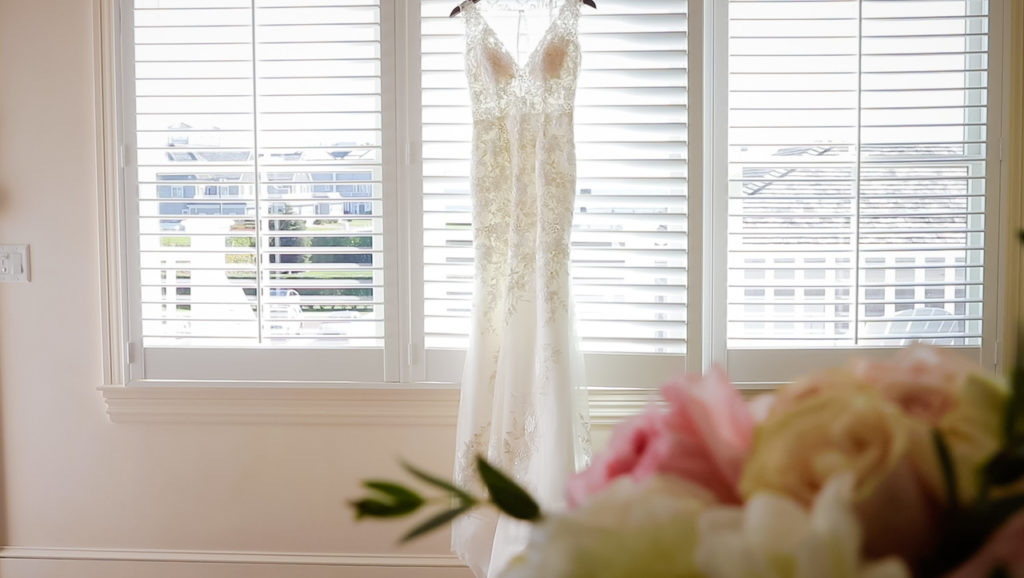 Delicate wedding dress hanging on window